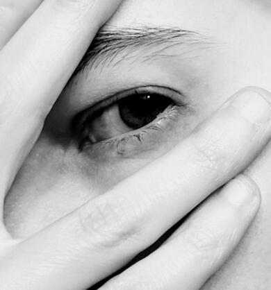 Black and white image of Ella, focusing on the eye. Fingers obscure part of the eyebrow and the cheek.